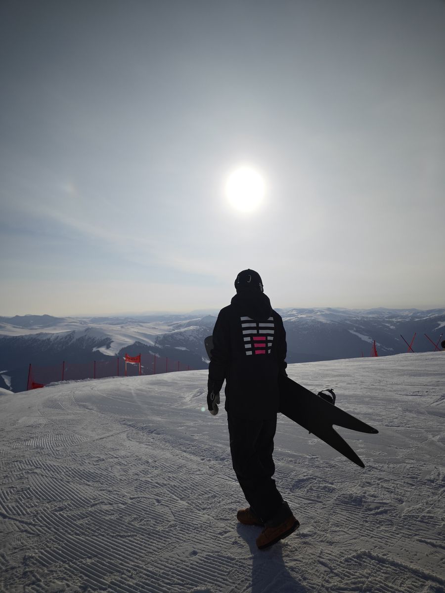 A rider walking into the sun with a swallowtail board